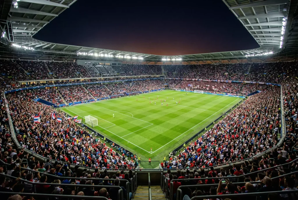 Packed football stadium at night with green pitch illuminated under floodlights before a World Cup 2026 match